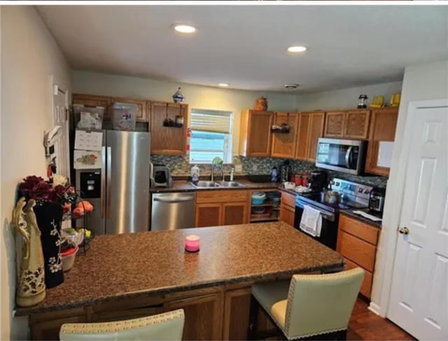 1096 Buchanan St, Des Moines, IA 50316 - kitchen featuring appliances with stainless steel finishes, a peninsula, brown cabinetry, backsplash, and a breakfast bar