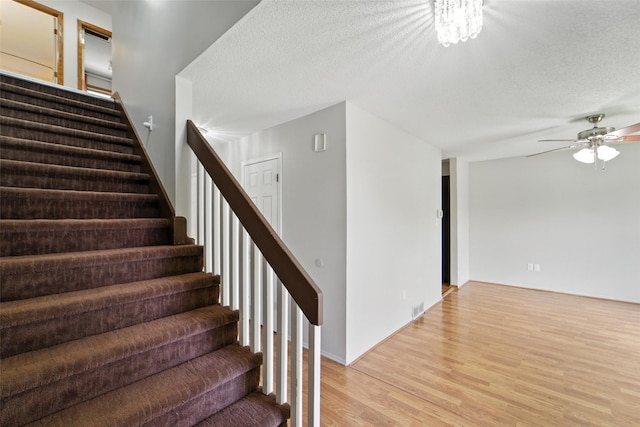 1228 64th St, West Des Moines, IA 50266 - staircase with wood finished floors, a ceiling fan, and a textured ceiling