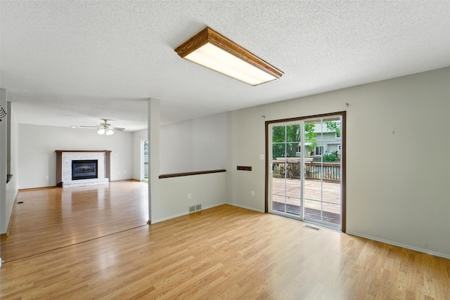 1228 64th St, West Des Moines, IA 50266 - unfurnished room featuring light wood finished floors, a textured ceiling, a brick fireplace, and a ceiling fan