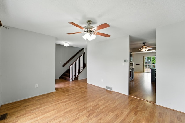 1228 64th St, West Des Moines, IA 50266 - empty room featuring ceiling fan, light wood finished floors, and stairway