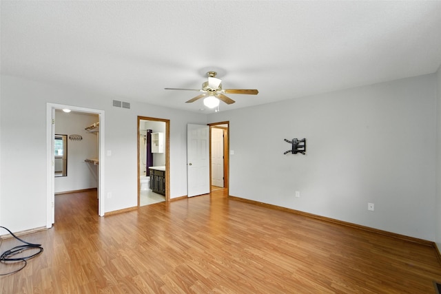 1228 64th St, West Des Moines, IA 50266 - unfurnished bedroom featuring a walk in closet, light wood finished floors, ceiling fan, connected bathroom, and a closet