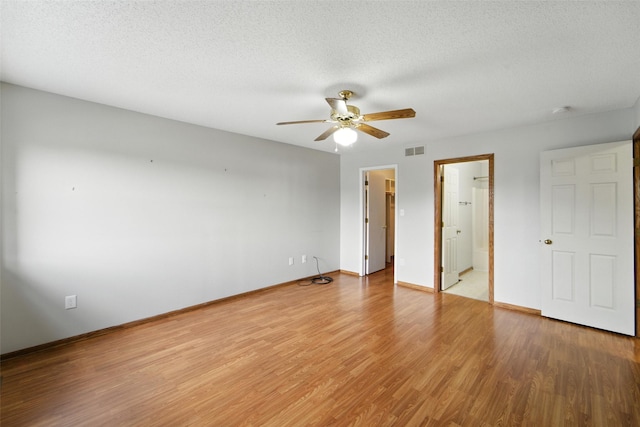 1228 64th St, West Des Moines, IA 50266 - unfurnished bedroom featuring light wood-style flooring, a walk in closet, a textured ceiling, ceiling fan, and a closet