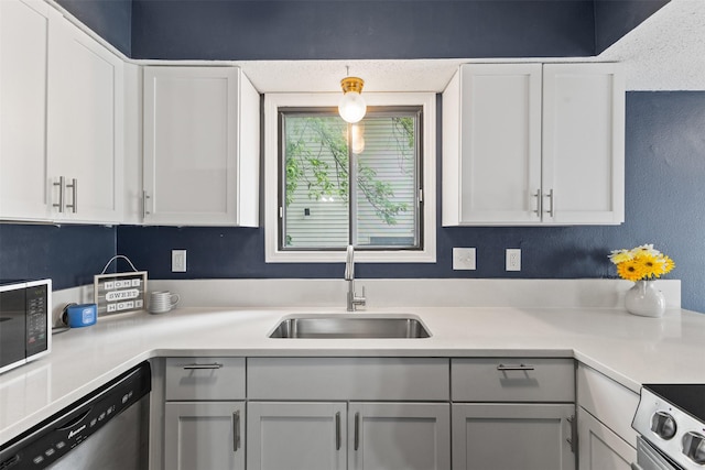 1913 E Bell Ave, Des Moines, IA 50320 - kitchen with stainless steel dishwasher, black microwave, light countertops, and white cabinets