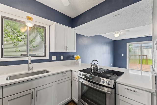 1913 E Bell Ave, Des Moines, IA 50320 - kitchen with stainless steel electric range, ceiling fan, a textured ceiling, light countertops, and white cabinetry