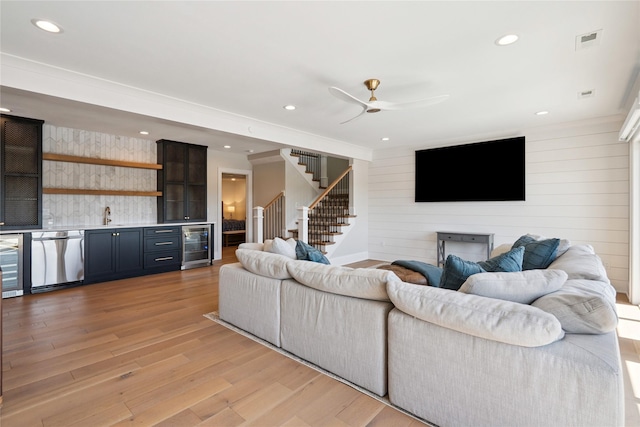 4387 Panorama Dr, Panora, IA 50216 - living room featuring bar with sink, beverage cooler, light wood-style flooring, stairs, and a ceiling fan