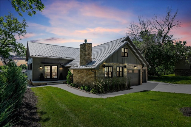 4387 Panorama Dr, Panora, IA 50216 - view of front facade featuring a chimney, stone siding, a lawn, driveway, and a standing seam roof