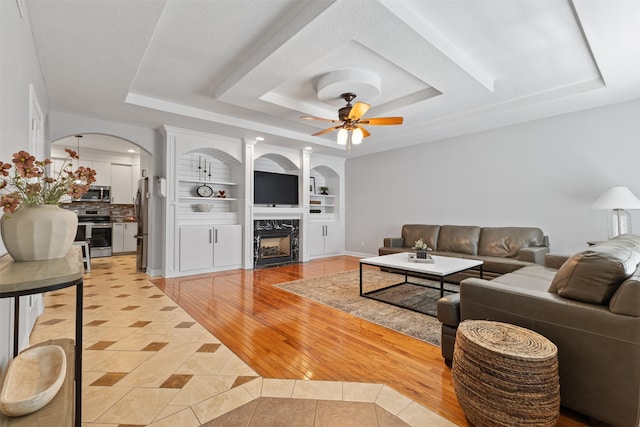 4315 129th St, Urbandale, IA 50323 - living room featuring a raised ceiling, light tile patterned floors, arched walkways, built in features, and a ceiling fan