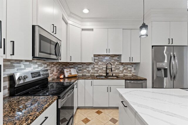 4315 129th St, Urbandale, IA 50323 - kitchen with appliances with stainless steel finishes, white cabinetry, pendant lighting, dark stone countertops, and ornamental molding