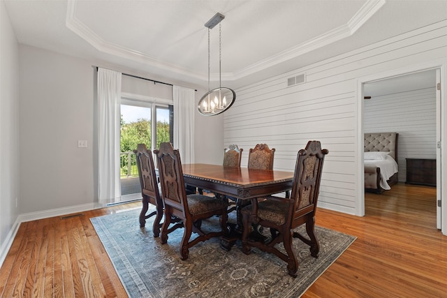 4315 129th St, Urbandale, IA 50323 - dining space with a chandelier, a tray ceiling, ornamental molding, wood finished floors, and wood walls