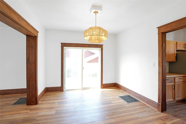 403 E 2nd St S, Newton, IA 50208 - unfurnished dining area with light wood-type flooring and a chandelier