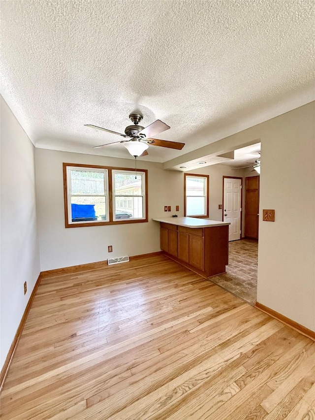 3355 Kinsey Ave, Des Moines, IA 50317 - unfurnished living room featuring a ceiling fan, light wood finished floors, and a textured ceiling