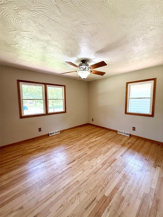 3355 Kinsey Ave, Des Moines, IA 50317 - unfurnished room with healthy amount of natural light, light wood-type flooring, a textured ceiling, and a ceiling fan