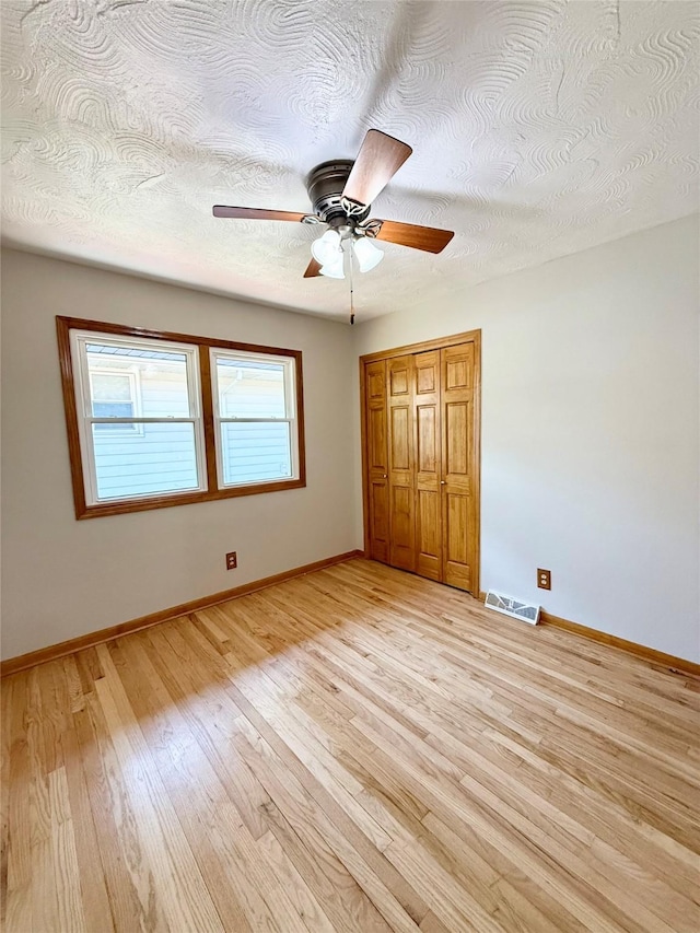 3355 Kinsey Ave, Des Moines, IA 50317 - unfurnished bedroom featuring light wood-style flooring, a textured ceiling, a ceiling fan, and a closet