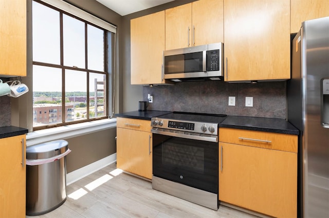 400 Walnut St Unit 901, Des Moines, IA 50309 - kitchen featuring stainless steel appliances, tasteful backsplash, dark countertops, and light wood-style flooring