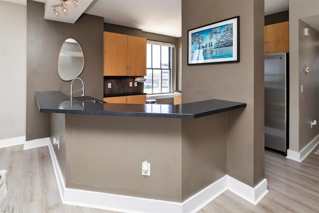 400 Walnut St Unit 901, Des Moines, IA 50309 - kitchen with freestanding refrigerator, dark countertops, a peninsula, light wood-type flooring, and tasteful backsplash