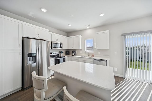 9529 Capstone Ct, West Des Moines, IA 50266 - kitchen with stainless steel appliances, dark wood-style floors, white cabinetry, a center island, and recessed lighting
