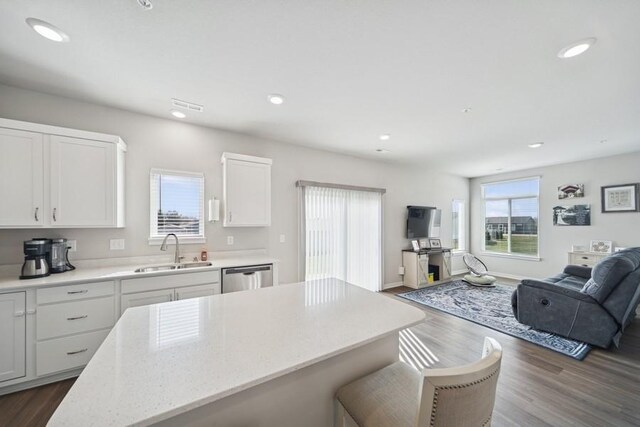 9529 Capstone Ct, West Des Moines, IA 50266 - kitchen with open floor plan, dishwasher, dark wood-type flooring, a kitchen bar, and white cabinetry