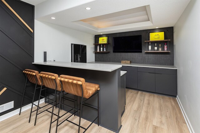 1286 Glen Oaks Dr, West Des Moines, IA 50266 - indoor dry bar featuring light wood finished floors, black fridge with ice dispenser, a raised ceiling, and recessed lighting