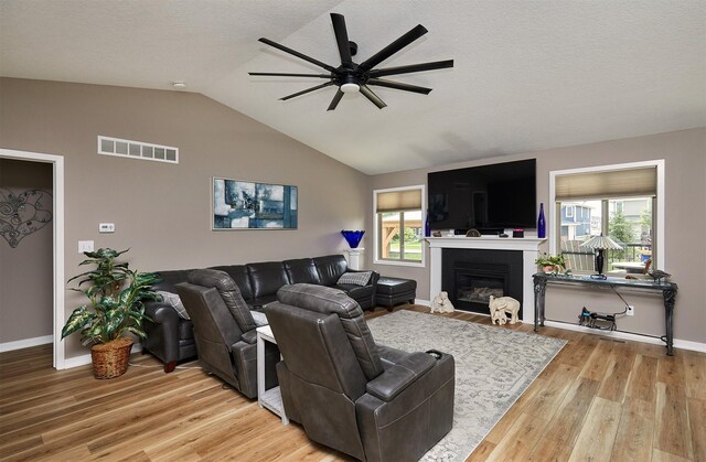 690 SE Driftwood Ln, Waukee, IA 50263 - living room with a ceiling fan, light wood-style floors, plenty of natural light, vaulted ceiling, and a glass covered fireplace