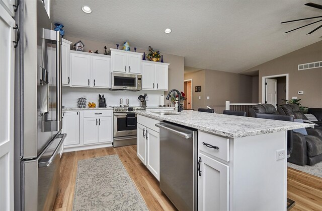 690 SE Driftwood Ln, Waukee, IA 50263 - kitchen with premium appliances, light wood-style flooring, white cabinetry, backsplash, and vaulted ceiling