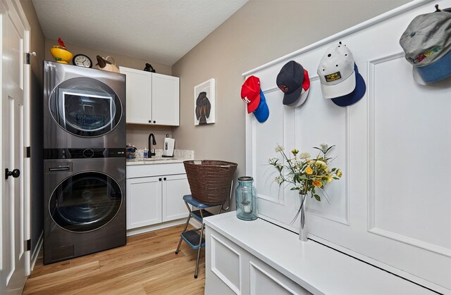 690 SE Driftwood Ln, Waukee, IA 50263 - laundry room featuring stacked washer and clothes dryer, cabinet space, and light wood-style flooring