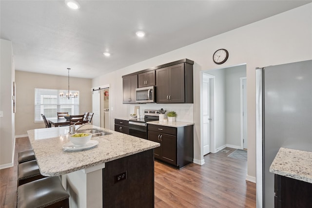 523 S Bluestone Way W, Des Moines, IA 50266 - kitchen with stainless steel appliances, light wood-style floors, a kitchen bar, dark brown cabinets, and recessed lighting