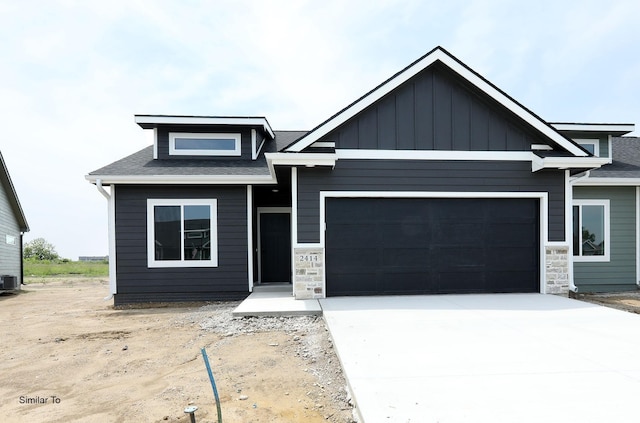 2410 NE 6th St, Grimes, IA 50111 - view of front of property with an attached garage, driveway, stone siding, and roof with shingles