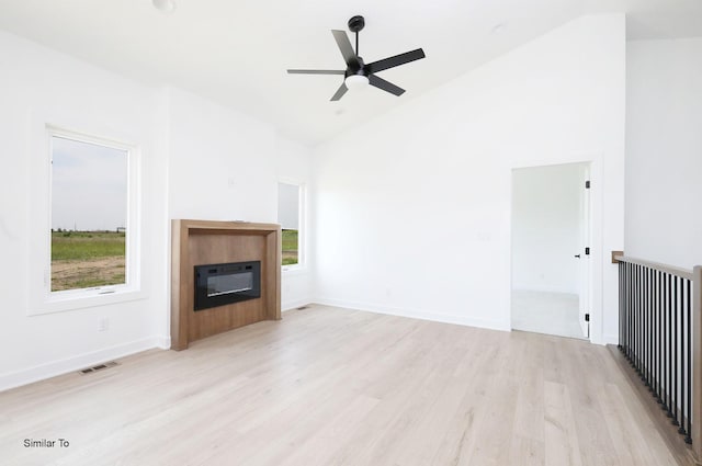 2410 NE 6th St, Grimes, IA 50111 - unfurnished living room featuring high vaulted ceiling, a glass covered fireplace, light wood finished floors, and a ceiling fan
