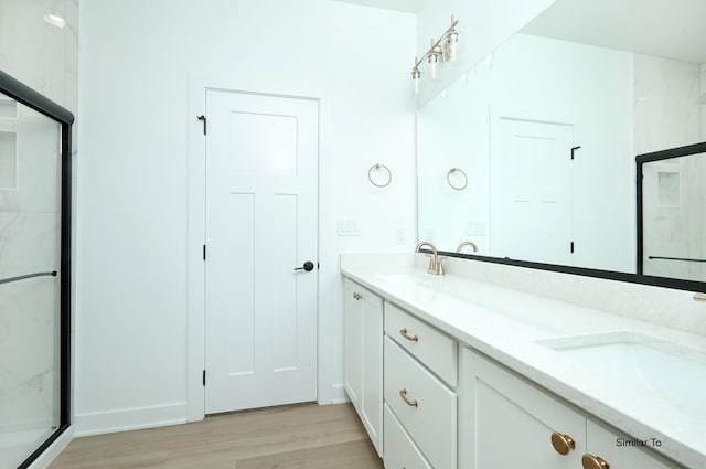 2410 NE 6th St, Grimes, IA 50111 - bathroom featuring double vanity, wood finished floors, and a shower with shower door