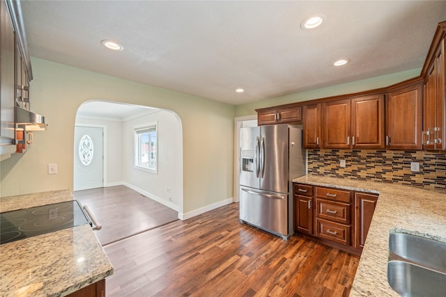2560 E Sheridan Ave, Des Moines, IA 50317 - kitchen with stainless steel fridge with ice dispenser, arched walkways, dark wood-style flooring, decorative backsplash, and recessed lighting