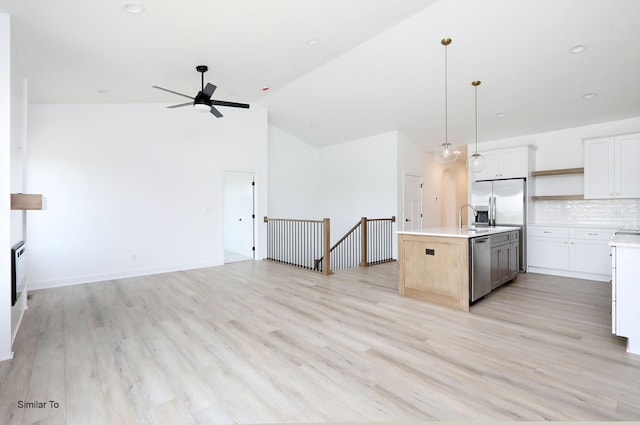 2408 NE 6th St, Grimes, IA 50111 - kitchen featuring open floor plan, a ceiling fan, light countertops, stainless steel appliances, and high vaulted ceiling