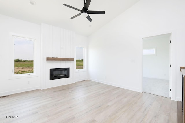 2408 NE 6th St, Grimes, IA 50111 - unfurnished living room featuring a large fireplace, light wood-style flooring, healthy amount of natural light, and lofted ceiling