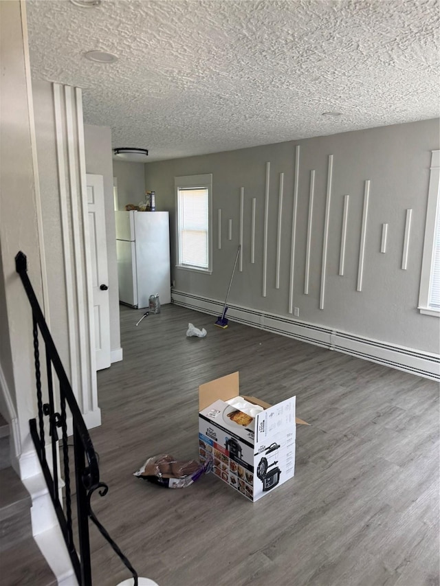 1008 Kingman Dr, Des Moines, IA 50311 - unfurnished living room with wood finished floors, a baseboard heating unit, and a textured ceiling