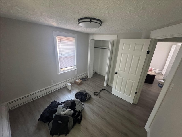 1008 Kingman Dr, Des Moines, IA 50311 - unfurnished bedroom featuring wood finished floors, a textured ceiling, a baseboard radiator, and a closet