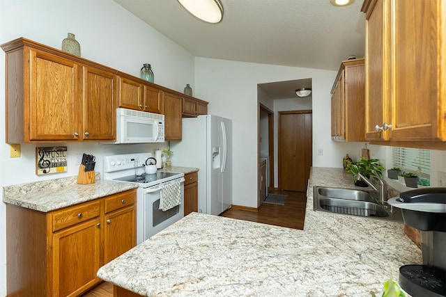 3540 E University Ave, Des Moines, IA 50317 - kitchen featuring white appliances, vaulted ceiling, light countertops, wood finished floors, and a peninsula