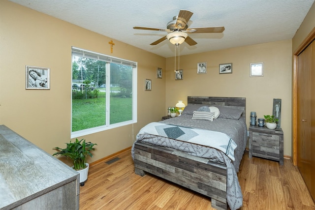 3540 E University Ave, Des Moines, IA 50317 - bedroom featuring light wood-style floors, a textured ceiling, and ceiling fan