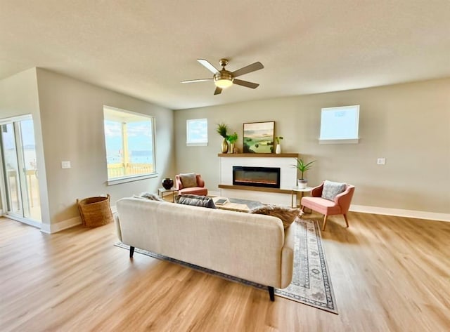 5610 Leyden Ave, Des Moines, IA 50317 - living room featuring light wood-style flooring, a glass covered fireplace, a ceiling fan, and a textured ceiling