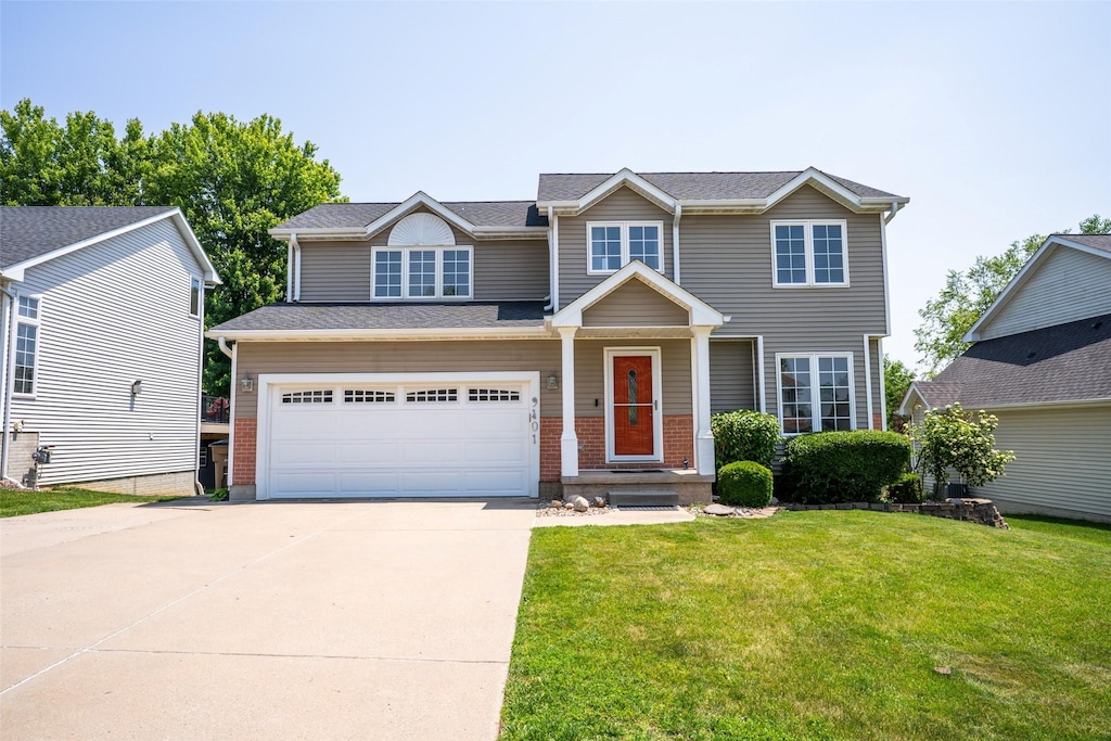 9401 Happy Hollow Dr, Norwalk, IA 50211 - view of front of house featuring driveway, a front lawn, an attached garage, and brick siding