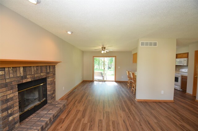 6020 NE 9th St, Des Moines, IA 50313 - unfurnished living room with wood finished floors, a fireplace, a textured ceiling, and ceiling fan