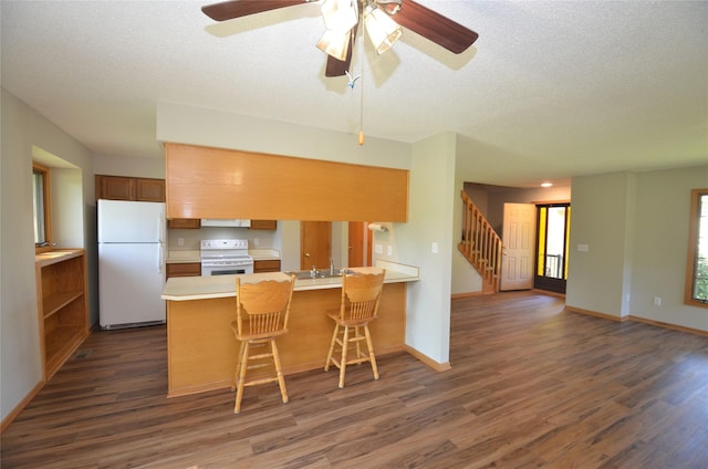 6020 NE 9th St, Des Moines, IA 50313 - kitchen with white appliances, a peninsula, dark wood-type flooring, light countertops, and a textured ceiling