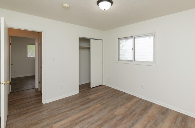 424/426 E Leach Ave, Des Moines, IA 50315 - unfurnished bedroom featuring light wood-style flooring, multiple windows, and a closet