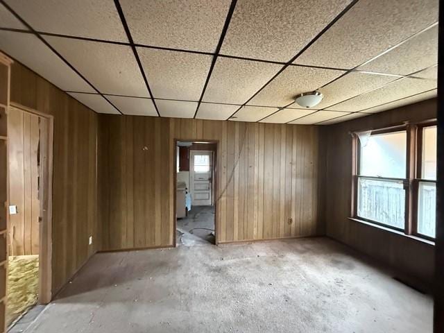603 N 1st Ave, Marshalltown, IA 50158 - unfurnished room featuring wood walls, a drop ceiling, and unfinished concrete flooring