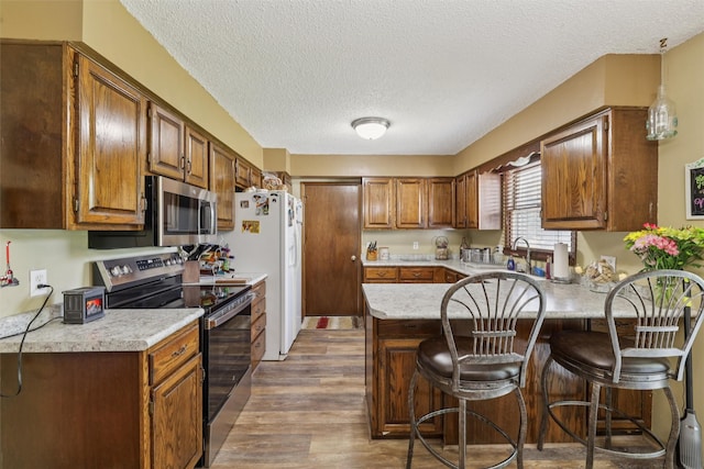 4200 SW 23rd Pl, Des Moines, IA 50321 - kitchen featuring appliances with stainless steel finishes, a peninsula, light countertops, wood finished floors, and a textured ceiling