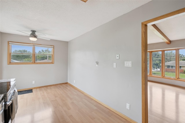 6843 NW 5th St, Des Moines, IA 50313 - unfurnished living room featuring light wood finished floors, plenty of natural light, ceiling fan, a textured ceiling, and beam ceiling