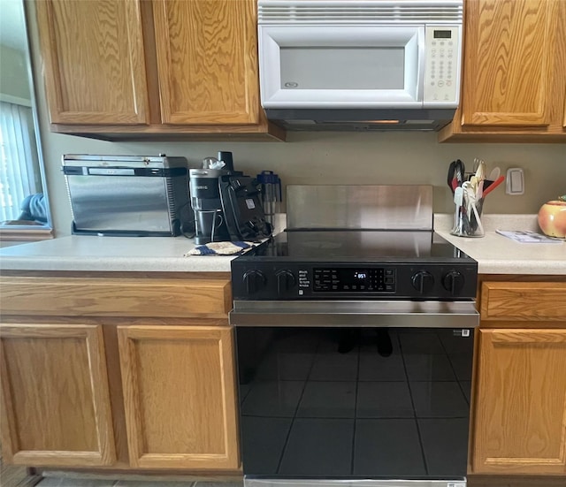 2101 Meadow Ct Unit 304, Des Moines, IA 50320 - kitchen featuring white microwave, electric stove, tile patterned floors, and light countertops