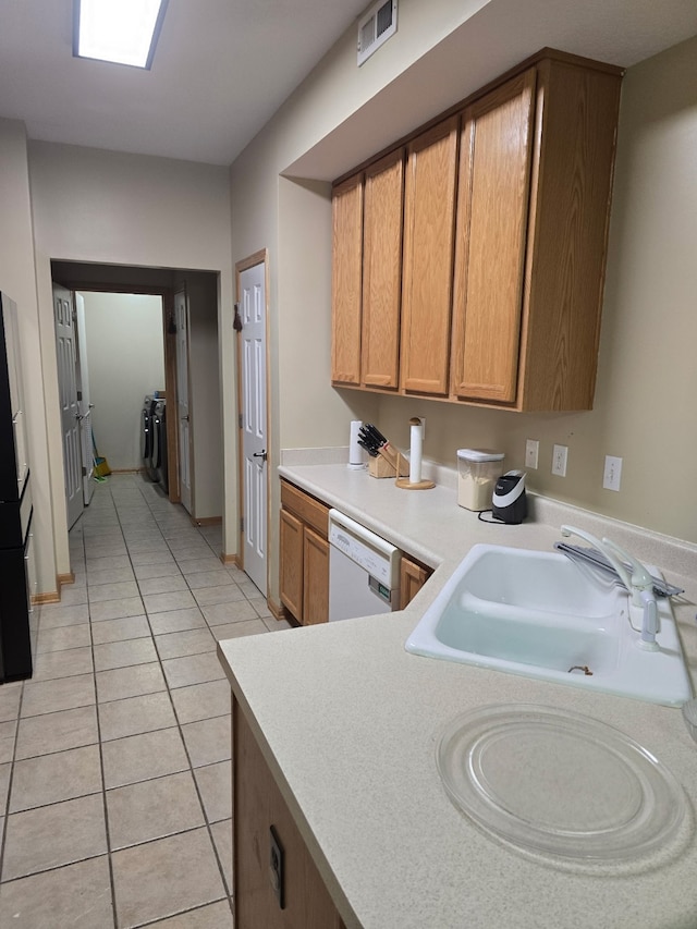 2101 Meadow Ct Unit 304, Des Moines, IA 50320 - kitchen with dishwasher, light countertops, light tile patterned floors, brown cabinetry, and freestanding refrigerator