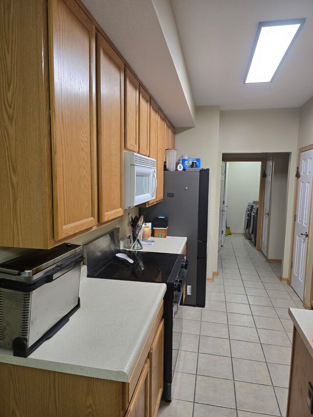 2101 Meadow Ct Unit 304, Des Moines, IA 50320 - kitchen featuring white microwave, black range with electric stovetop, light tile patterned floors, light countertops, and brown cabinets