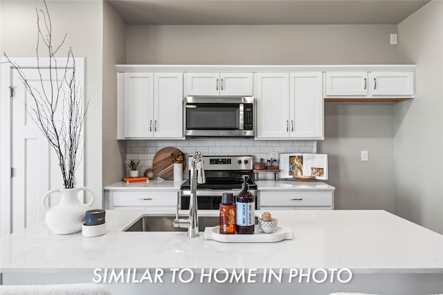 1488 S 91st St, West Des Moines, IA 50266 - kitchen with stainless steel appliances, light countertops, decorative backsplash, and white cabinets