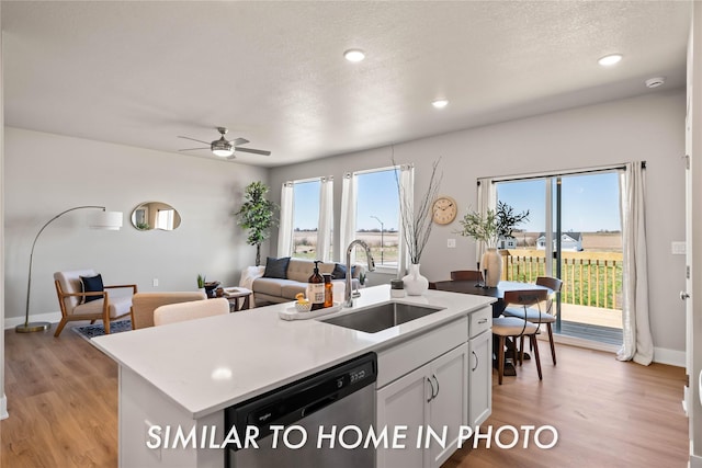 1488 S 91st St, West Des Moines, IA 50266 - kitchen featuring dishwashing machine, light wood finished floors, a kitchen island with sink, white cabinets, and light countertops