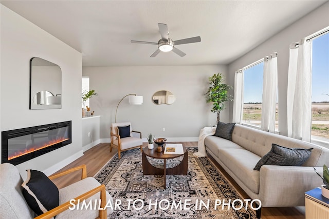1488 S 91st St, West Des Moines, IA 50266 - living room featuring healthy amount of natural light, wood finished floors, a glass covered fireplace, and ceiling fan